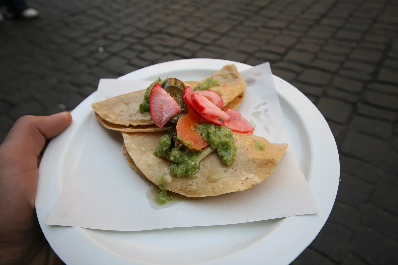 Two street tacos topped with green salsa and tomato. The photo was not taken at a Woodstock restaurant.