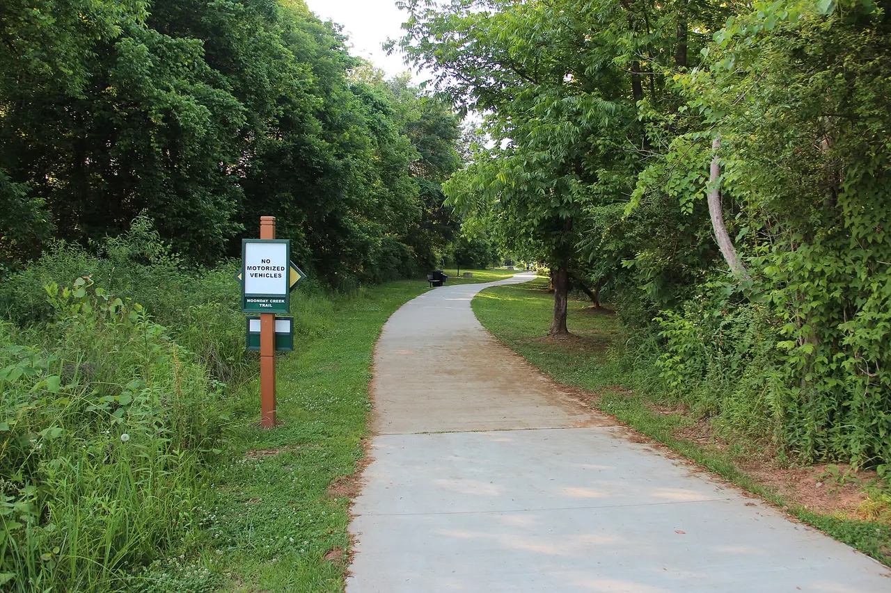 The paved Noonday Creek Trail through summer woods in Woodstock